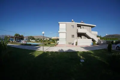 a white building with a grassy yard in front of it at Niovi Seaside Suites in Kissamos