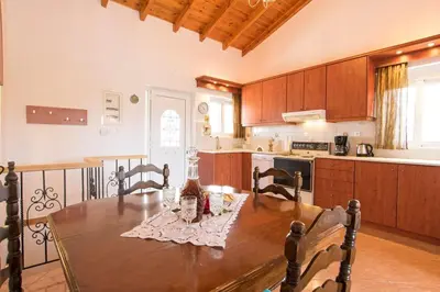 a kitchen with a wooden table with chairs and a table at Ortaki Traditional House in Loúlos