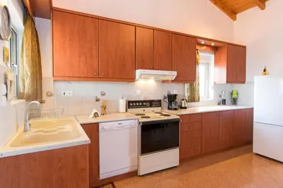 a kitchen with white appliances and wooden cabinets at Ortaki Traditional House in Loúlos