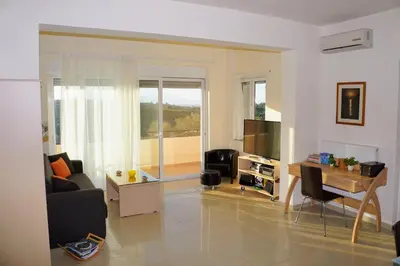 a living room with a couch and a table and a television at Olive Tree Hillside Apartment in Stalos