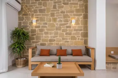 a couch with orange pillows sitting in front of a brick wall at Esplanade Apartments - Heated Pool in Kalathas
