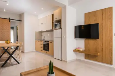 a kitchen with a table and a television on a wall at Esplanade Apartments - Heated Pool in Kalathas