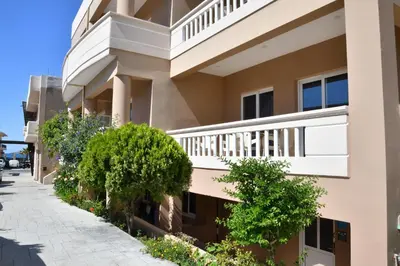 a building with balconies and trees on a sidewalk at Akatos Hotel in Agia Marina Nea Kydonias