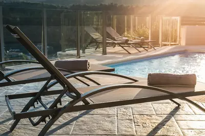 a pool with two lounge chairs next to a swimming pool at Villa Piedra in Manoliópoulon