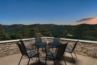 a table and chairs on a balcony with a view at Villa Piedra in Manoliópoulon