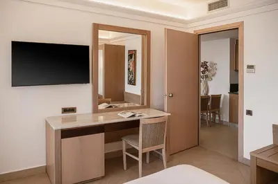 a hotel room with a desk and a television at Porto Platanias Beach Resort & Spa in Plataniás