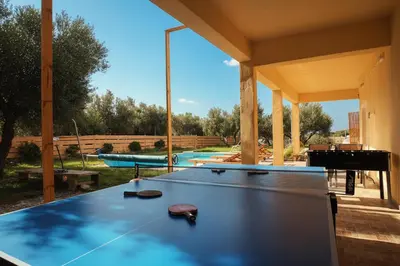 a ping pong table in a backyard with a pool at White Lake Holiday House in Elafonisi