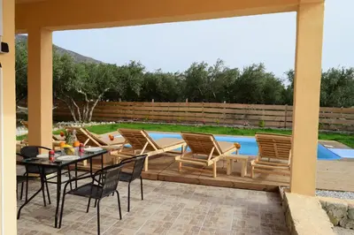 a patio with a table and chairs and a pool at White Lake Holiday House in Elafonisi