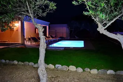 a backyard with a swimming pool at night at White Lake Holiday House in Elafonisi