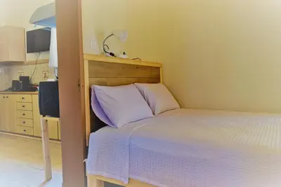 a small bedroom with a bed with purple pillows at White Lake Holiday House in Elafonisi