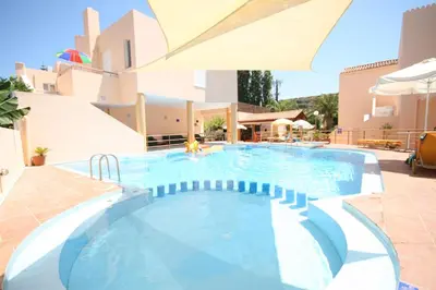 a swimming pool in a resort with an umbrella at Elma's Dream Apartments & Villas in Kato Daratso
