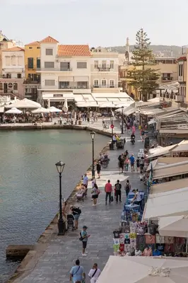 a group of people walking on a street next to a body of water at Lucia Hotel in Chania Town