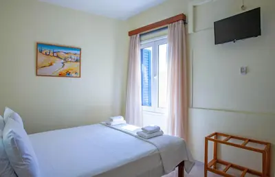 a bedroom with a white bed and a window at Lucia Hotel in Chania Town