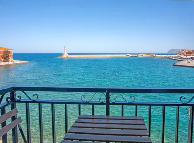 a bench sitting on top of the water with a lighthouse at Lucia Hotel in Chania Town