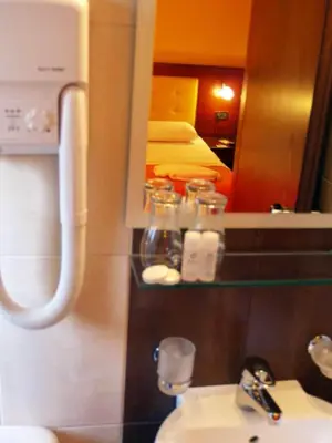 a bathroom with a sink and a mirror and a bed at Hotel Filoxenia in Chania Town