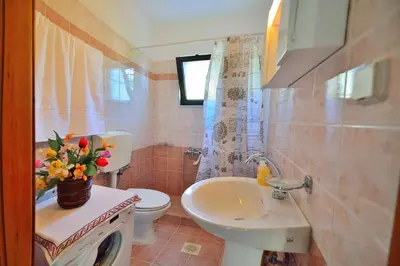 a bathroom with a sink and a toilet with a vase of flowers at Archontiko Ilias in Kavoúsion