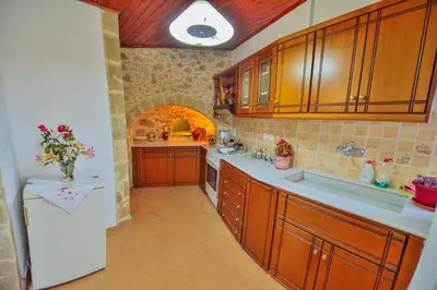 a large kitchen with wooden cabinets and a white refrigerator at Archontiko Ilias in Kavoúsion