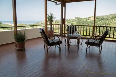 a room with chairs and a table and a balcony at Alexandra Villa Stalos in Stalos