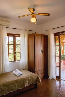 a bedroom with a bed with a ceiling fan and windows at Alexandra Villa Stalos in Stalos