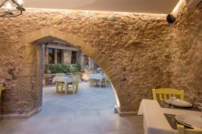 a stone wall with an archway in a restaurant at Spilia Village Hotel & Villas in Spiliá