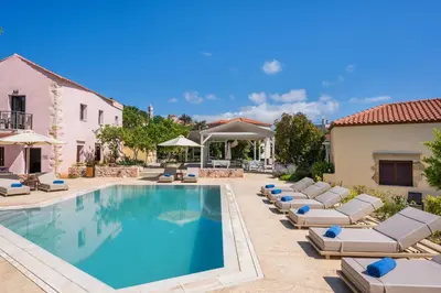 a swimming pool with chaise lounge chairs and a resort at Spilia Village Hotel & Villas in Spiliá