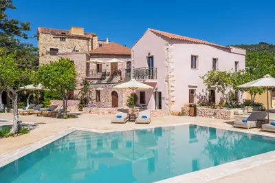 a villa with a swimming pool and a house at Spilia Village Hotel & Villas in Spiliá