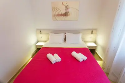 a bedroom with a red bed with two slippers on it at Eleni Apartments in Chania Town