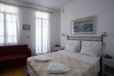 a bedroom with a bed and a red chair at Nostos Hotel in Chania Town