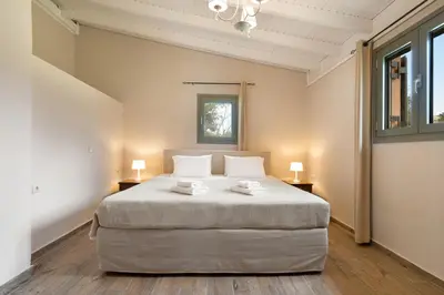 a bedroom with a large bed in a room with windows at Villa Adriana in Arménoi