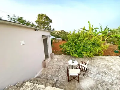 a patio with a table and chairs next to a building at MG Cozy Garden View Studio in Korakiaí