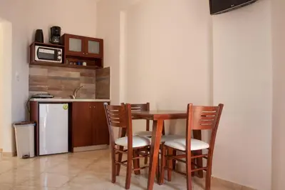 a kitchen with a table and chairs and a refrigerator at Ekavi Apartments in Agia Marina Nea Kydonias