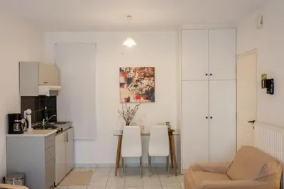 a kitchen with white cabinets and a table and chairs at Halepa Studios in Chania Town