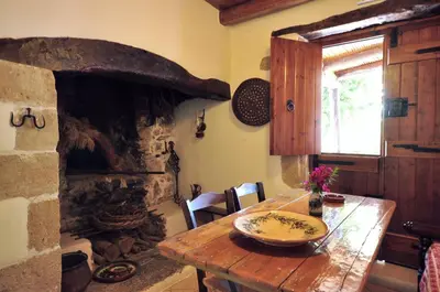 a kitchen with a wooden table with a stone fireplace at Elia Hotel & Spa in Áno Voúvai