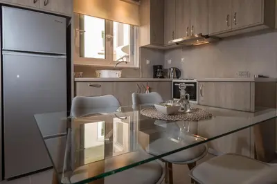 a kitchen with a glass table and white chairs at AnDi's Apartment's Paleochora in Palaiochóra
