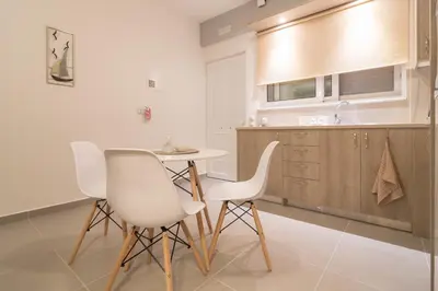 a kitchen with a table and two white chairs at AnDi's Apartment's Paleochora in Palaiochóra