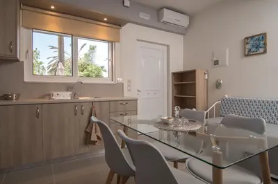 a kitchen and dining room with a glass table and chairs at AnDi's Apartment's Paleochora in Palaiochóra