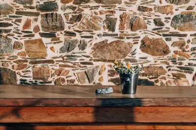 a vase of flowers sitting on a wooden bench against a stone wall at Captain Nikolas in Keramotí