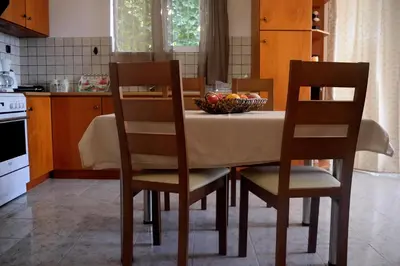 a kitchen with a table with chairs and a bowl of fruit at Apartment next to the beach in Kato Daratso