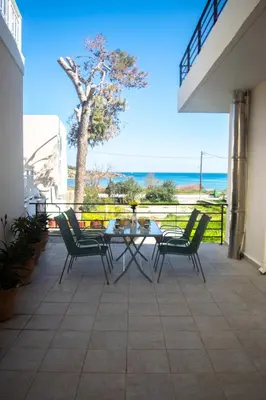a patio with a table and chairs and the ocean at Apartment next to the beach in Kato Daratso