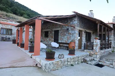 a stone house with a porch and chairs in front of it at Mike Omalos Houses in Omalós