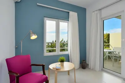 a blue living room with a chair and a table at Casa Manolesos in Chorafakia