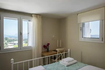 a bedroom with a bed and a desk and windows at Margiani House in Kaláthenai