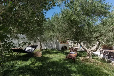 a yard with two chairs and some trees at Margiani House in Kaláthenai