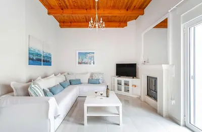 a white living room with a white couch and a fireplace at Villa Despina in Kisamos in Kissamos