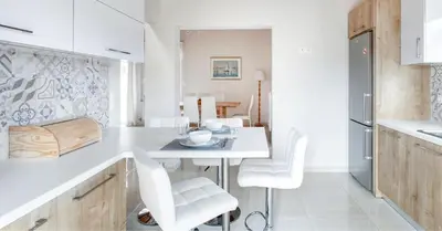 a white kitchen with a table and white chairs at Villa Despina in Kisamos in Kissamos