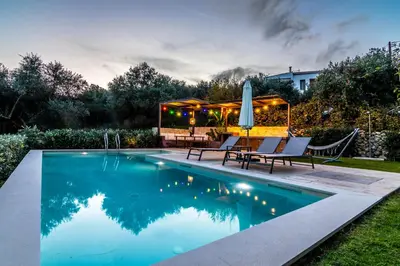 a swimming pool with chairs and a table and a umbrella at Apithano Heated pool on demand in Spiliá