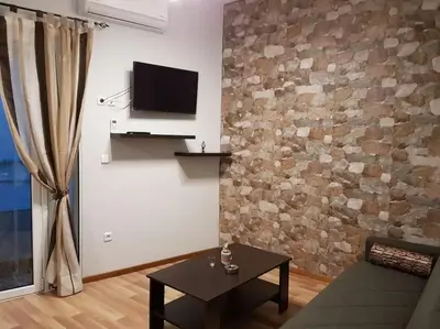 a living room with a tv on a brick wall at Agora Apartment First Floor in Kissamos