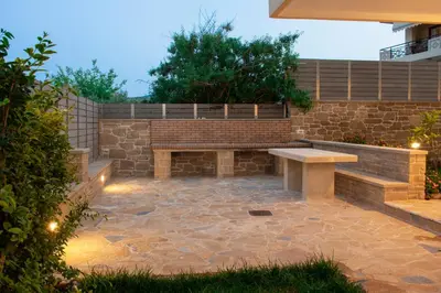a patio with a bench and a stone wall at Christina Apartment in Kissamos