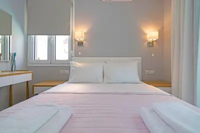 a bedroom with a large white bed with two pillows at Sonja Beachfront Apartments in Kato Daratso