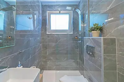 a bathroom with a shower and a toilet and a sink at Sonja Beachfront Apartments in Kato Daratso
